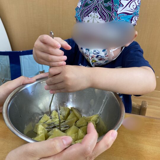 サツマイモをつぶす2歳児