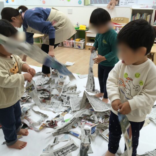 星のおうち幕張北の室内で新聞を使って遊ぶ0～2歳児の様子